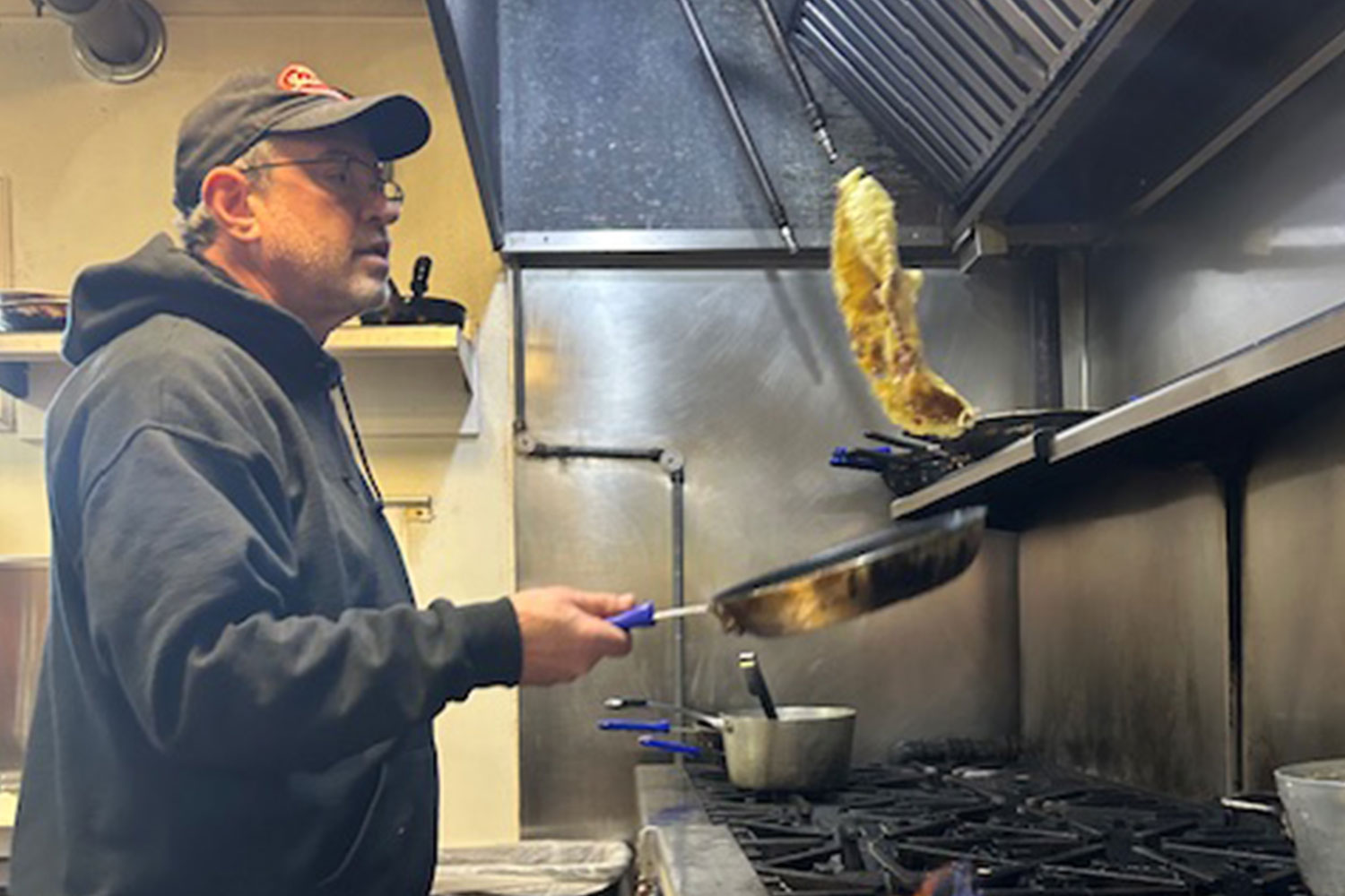 Stephen Jacobs flipping food over oven