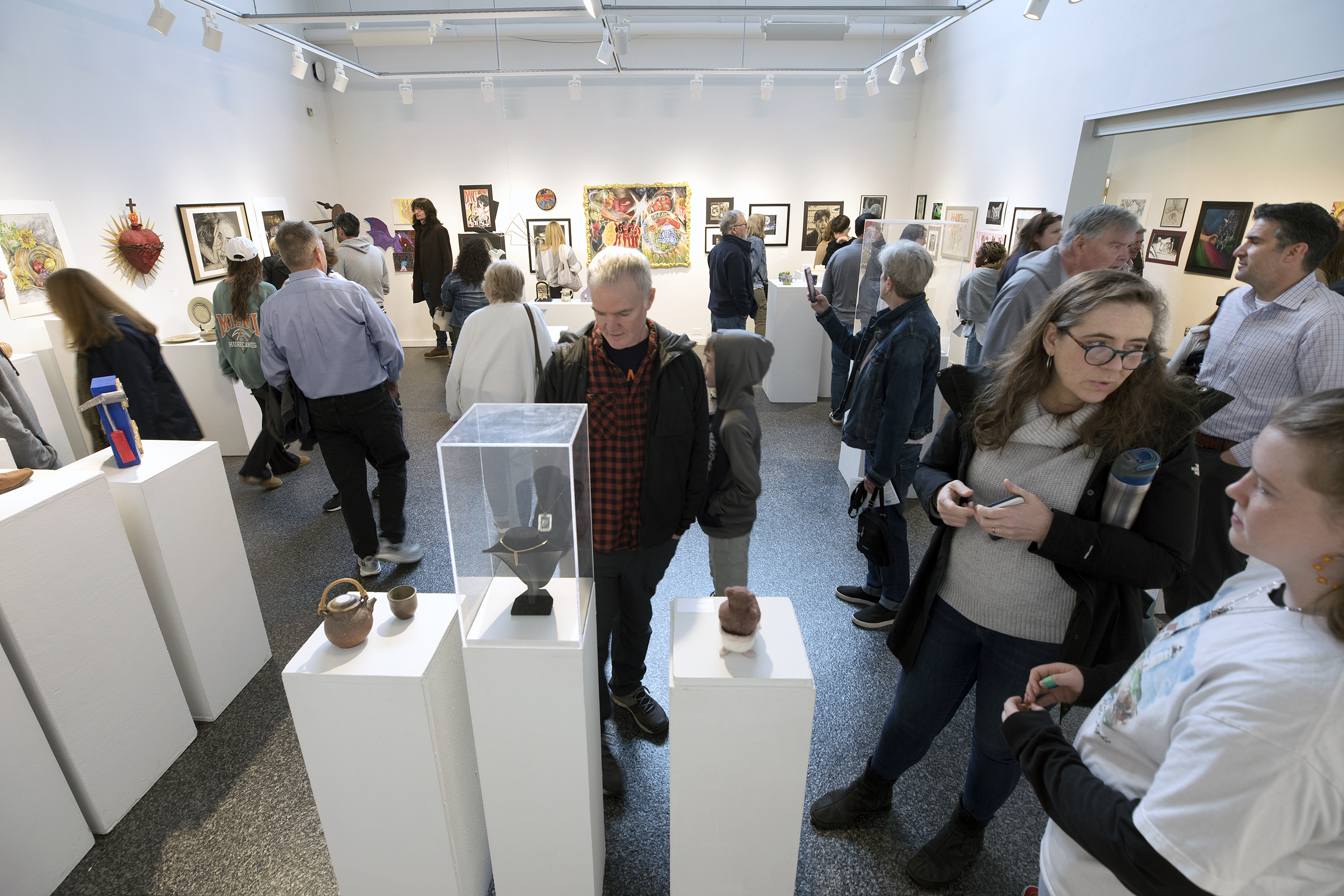 Crowd attending and viewing last years high school art exhibition gallery.