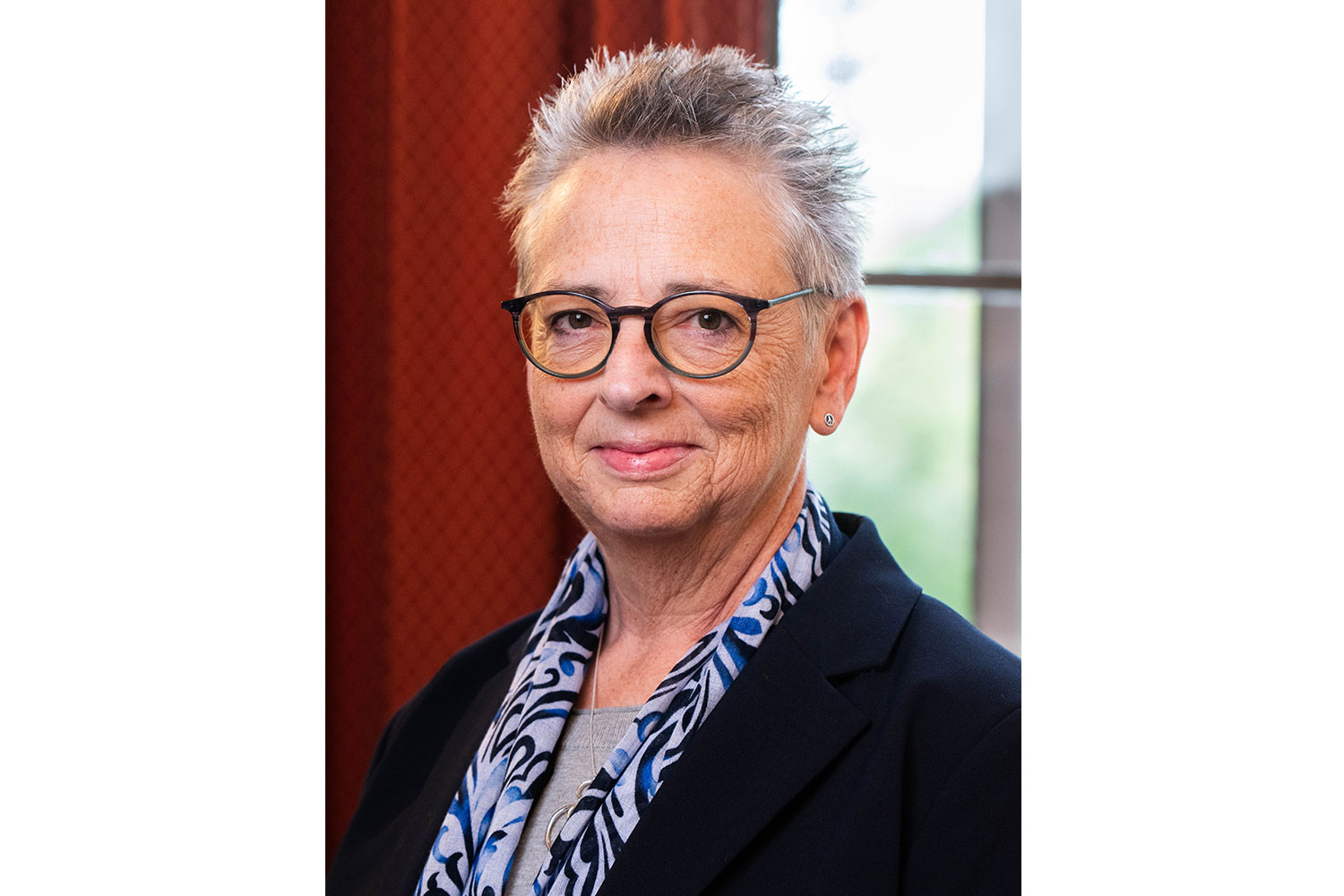 Portrait of Deborah Armstrong wearing a dark blazer and patterned scarf.