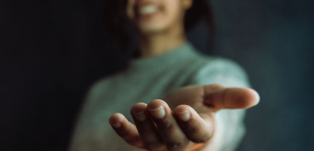 A person reaches forward with an outstretched hand.