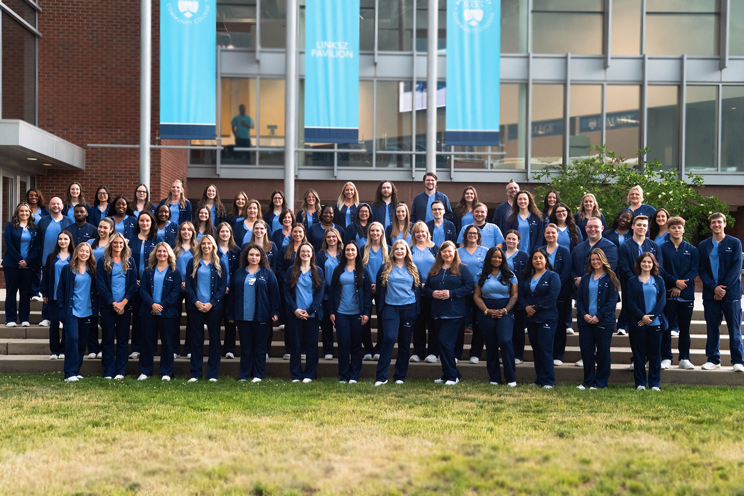 Associate Degree Nursing graduates wearing matching blue uniforms and white shoes stand outside the Linksz Pavillion.