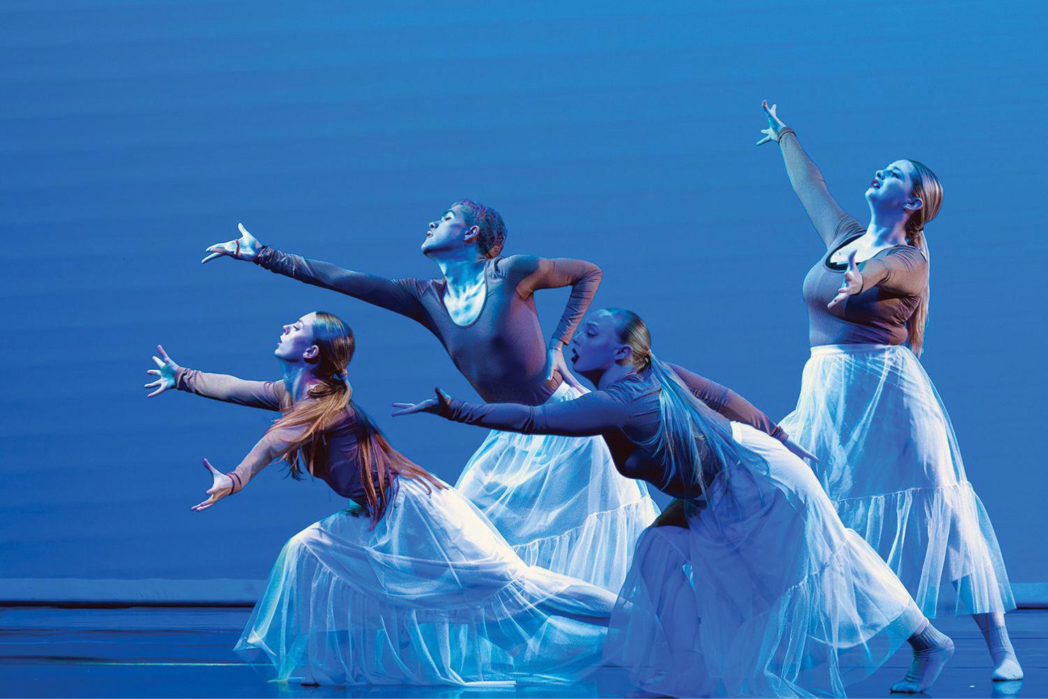 dancers performing under blue lighting