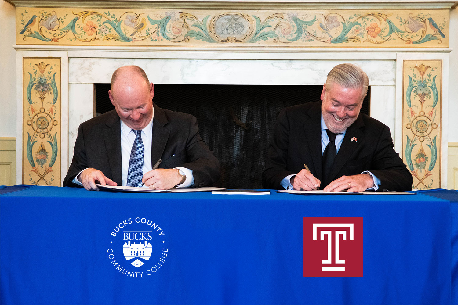 Presidents Jones and Fry in suits, seated at a table draped in a blue cloth with